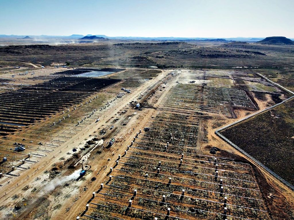 Mooiplaats solar PV project: Piling and tracker foundations under construction beside a completed solar array at Mooiplaats