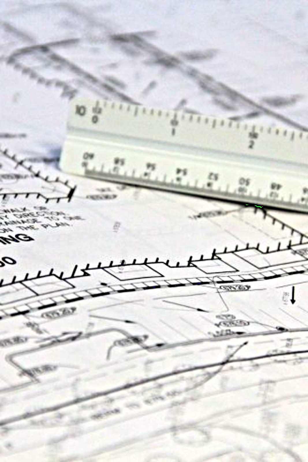 Detailed close-up of architectural blueprints with scale ruler, showing building plans and measurements.