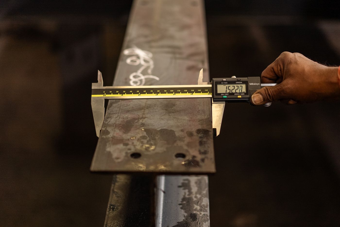 Digital caliper measuring a steel beam as part of a quality check